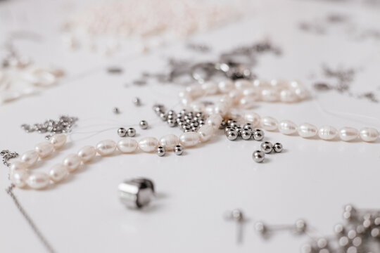 Close-up of jewelry making supplies - pearls, metal beads, and crafting tools on a white background close up
