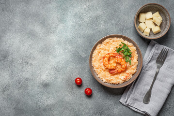 Risotto with shrimps in a bowl on grey grunge background, top view, flat lay, copy space