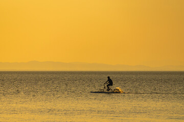 Fototapeta premium Man riding water bike across Lake Cocibolca at golden sunset, Nicaragua