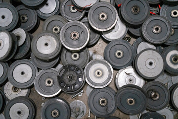 Close-up shot of multiple damaged black rubber wheels with bearings, scattered on a surface with some metal components visible.