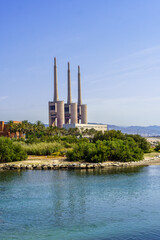 Obraz premium Panoramic View of Sant Adriá Thermal Power Station with its Three Imposing Chimneys under the Blue Sky”