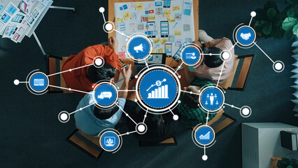 A diverse group engaged in a collaborative strategy session, using visual data and marketing concepts to drive innovation and growth in a professional office setting. Amity