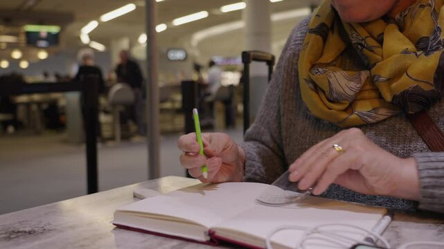 Woman erasing notes in her book, using protractor while waiting at airport