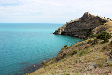Rocky coastline meeting turquoise water under cloudy sky