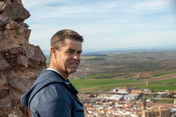 Naklejka premium A man is standing confidently on top of a cliff, overlooking a beautiful city
