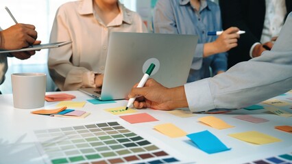 A dynamic office scene showcasing a diverse group of professionals engaged in a collaborative brainstorming session, utilizing laptops and colorful sticky notes for planning. SACTR