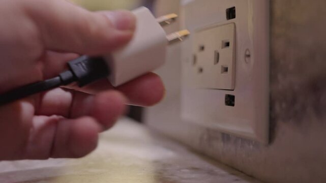 Removing a usb cable adapter from an ac wall socket in a modern living space