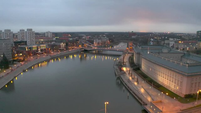 Early morning view of Wroclaw Grunwaldzki Bridge and Oder river waterfront with city lights and cloudy sky. urban landscape