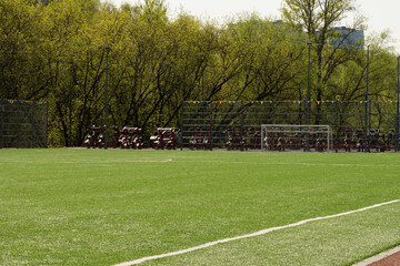 Soccer goal on big field with artificial green grass. Summer season. Outdoor sports activities.