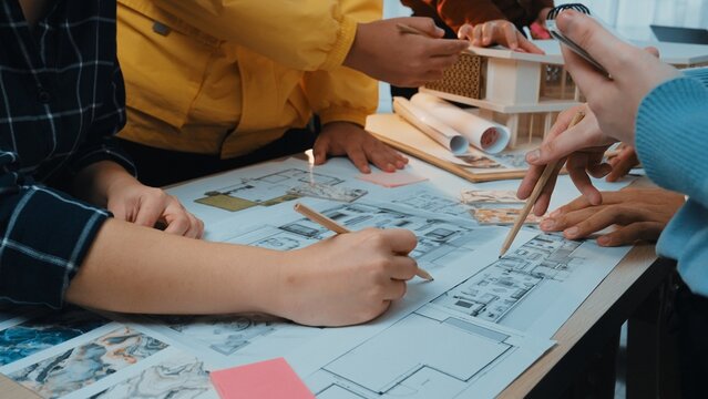 A dynamic workshop scene highlighting collaboration in architecture as diverse individuals engage in sketching blueprints, sharing ideas, and using various materials. SACTR