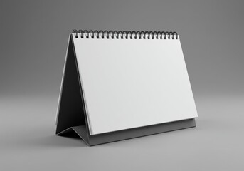Spiral-bound desk calendar mockup with blank white pages angled on gray surface with soft shadow