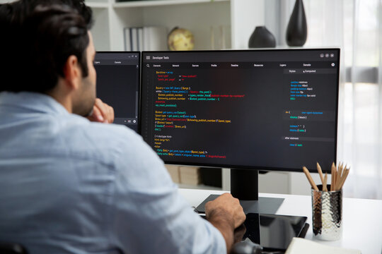 Concentrating in smart IT developer working software development coding on two pc screen, creating virus firmware application program for latest update version on website at modern office. Surmise.