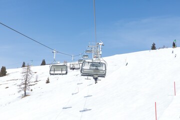 Obraz premium Ski lift on snowy mountain under clear blue sky on winter day