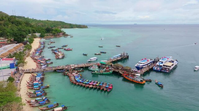 Tourists gather on bustling dock at Phi Phi Island, Thailand. Aerial drone video