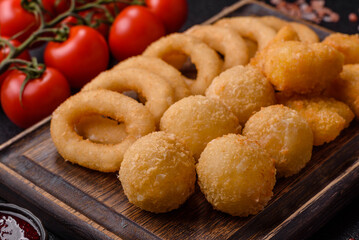 Food, chicken nuggets, onion rings and cheese balls on dark background