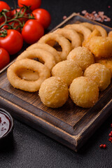 Food, chicken nuggets, onion rings and cheese balls on dark background