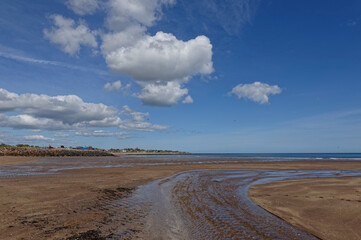 The Barry Burn outlet crossing the sandy beach at Carnoustie during a falling tide, with the Town in the distance facing the North Sea.