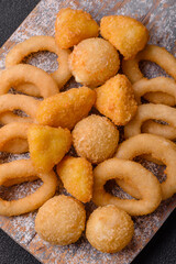 Food, chicken nuggets, onion rings and cheese balls on dark background
