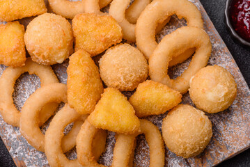 Food, chicken nuggets, onion rings and cheese balls on dark background