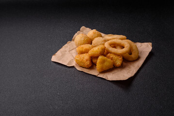 Food, chicken nuggets, onion rings and cheese balls on dark background