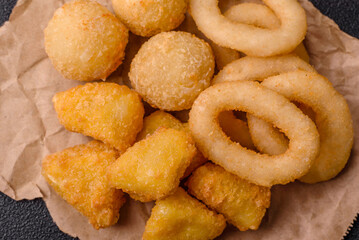 Food, chicken nuggets, onion rings and cheese balls on dark background
