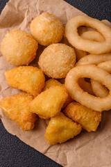Food, chicken nuggets, onion rings and cheese balls on dark background