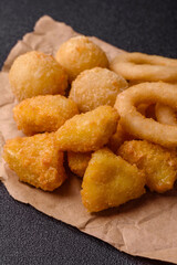 Food, chicken nuggets, onion rings and cheese balls on dark background