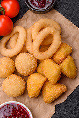 Food, chicken nuggets, onion rings and cheese balls on dark background