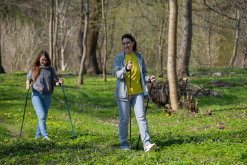 two women walking in the forest with sticks, Nordic walking, lesbians doing sports, couple in love	