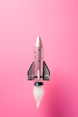 Pink rocket model on pink background with reflection. Space exploration and girl power concept. Toy spacecraft for science education and astronomy inspiration