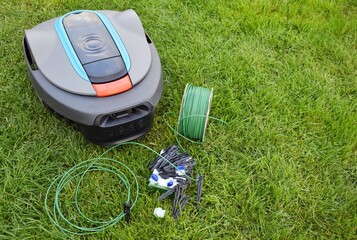 Roll of wire for robotic lawn mower, plastic pegs, connectors and robot.
