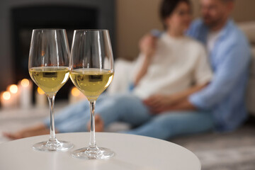 Couple near fireplace at home, focus on glasses of wine