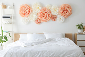 Beautiful decorative paper flowers on wall in bedroom