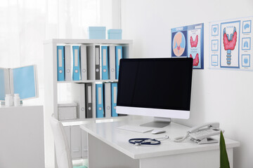 Fototapeta premium Clipboard, pen, computer, telephone and stethoscope on desk in doctor's office
