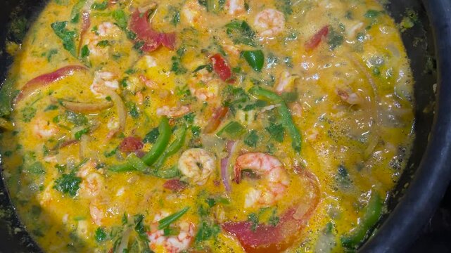 shrimp moqueca in coconut milk with seasonings and palm oil cooking. shrimp stew.