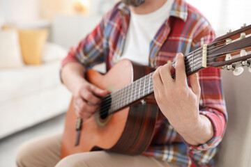Obraz premium Man playing guitar at home, focus on hand