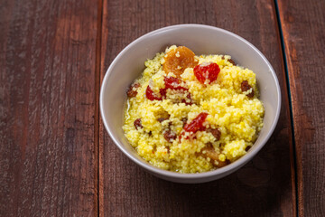 Steamed couscous with dogwood, nuts and raisins in a plate on the table