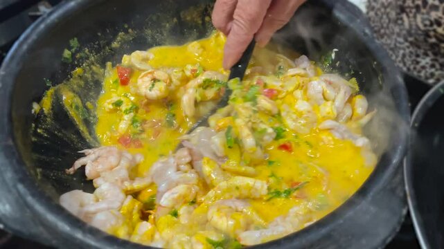 preparing shrimp moqueca in coconut milk with seasonings and palm oil. shrimp stew.