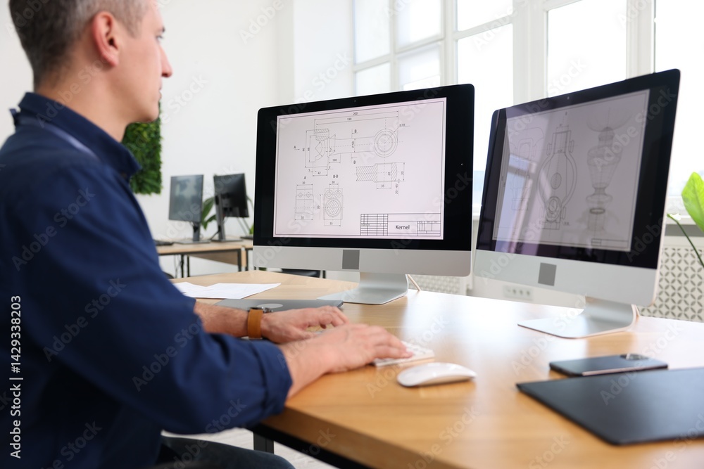 Poster engineer working with digital drawings at table in office