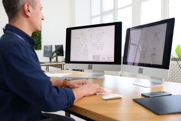 Engineer working with digital drawings at table in office