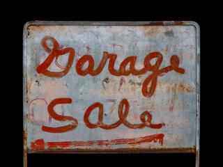 Old and weathered garage sale sign with red lettering and rustic charm