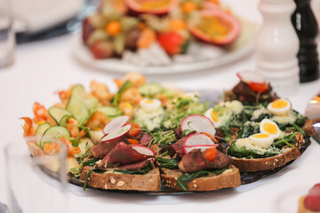 Assorted gourmet canapés with quail eggs, shrimp, meat, and fresh greens on a festive platter