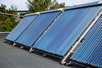 А solar water heating collectors, equipped with blue vacuum tubes, are installed on a rooftop to harness solar energy, converting it into heat for domestic heating and  hot water systems © Sodel Vladyslav