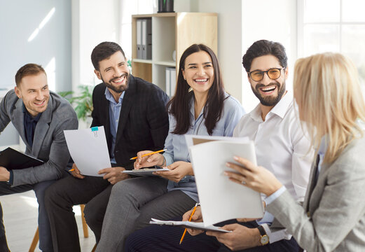 Positive group of a business people in team working together in office, laughing during conversation in meeting or conference, focusing on collaboration in a professional setting with joy.