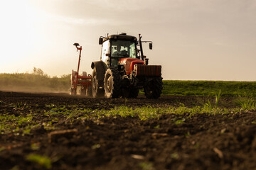 Obraz premium Farmer with tractor seeding in sunset