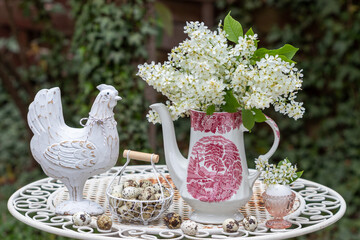 Oster-Arrangement mit  Blumenstrauß aus Traubenkirsche (Prunus padus), Osterhuhn und Wachteleiern