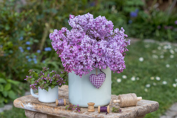 Flieder-Strauß (Syringa) im vintage Milchkrug und Schwarznessel (Ballota nigra) in einer...