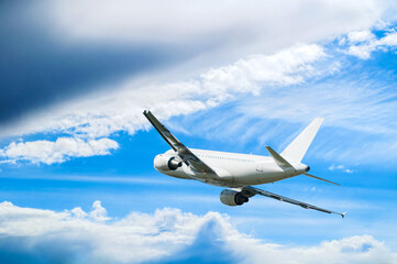 Airplane flying in the sky - travel background with white commercial airplane in flight, travel by air concept