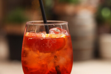 Aperol Spritz. Cold refreshing alcoholic cocktail Aperol Spritz. Cocktail close-up on a blurred background. Alcoholic drink in a glass with a straw. Traditional Italian alcoholic refreshing drink