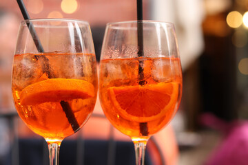 Aperol Spritz. Cold refreshing alcoholic cocktail Aperol Spritz. Cocktail close-up on a blurred background. Alcoholic drink in a glass with a straw. Traditional Italian alcoholic refreshing drink